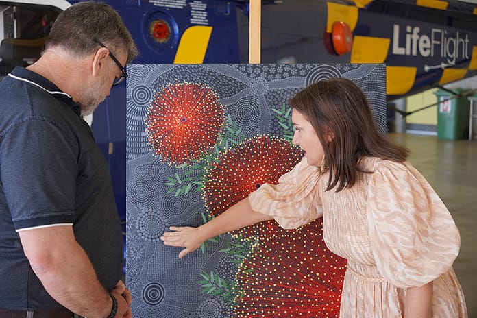 1 First Nations artist Melinda Luscombe explains her painting to LifeFlight Toowoomba base lead Scott Nicholls